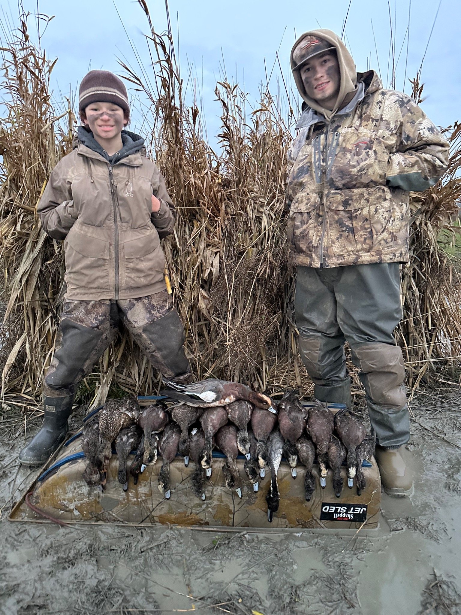 Two hunters with ducks in a cornfield