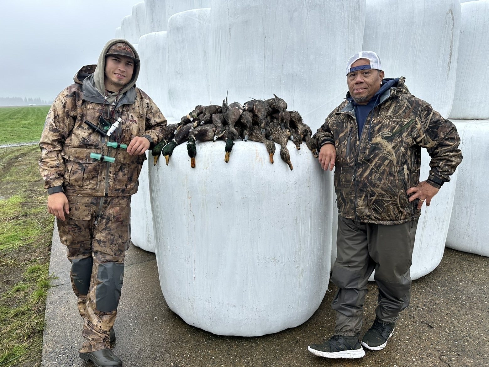 Two hunters with harvested ducks in a field