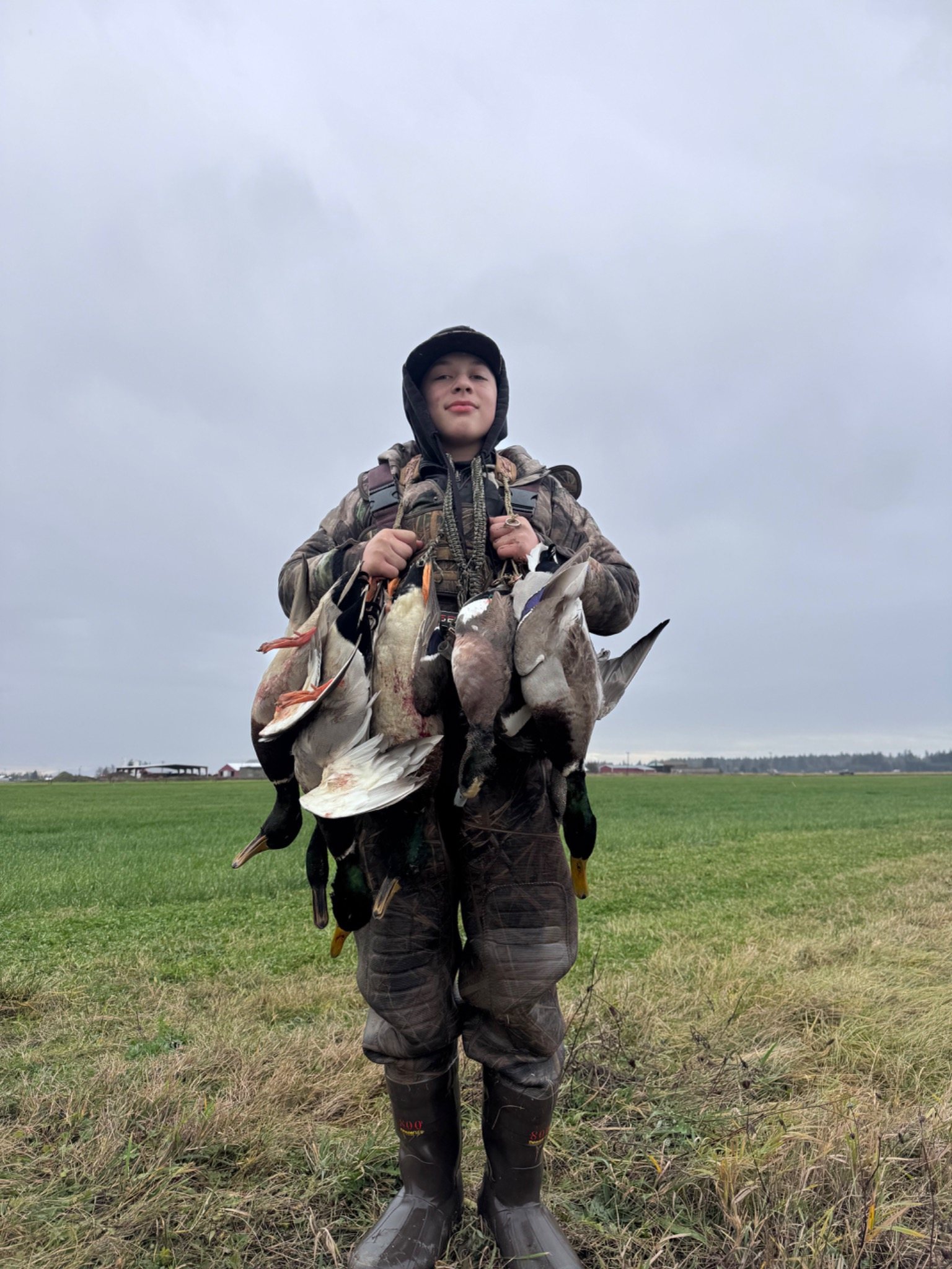 Young hunter holding harvested ducks in a field